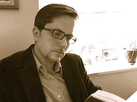 Steven E. Lindquist reading a book in front of a window