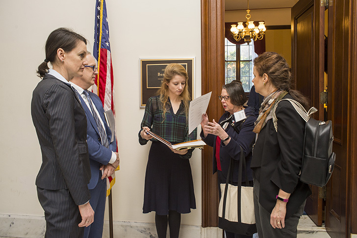 A group of five humanities advocates talk together outside an office door at the Capitol