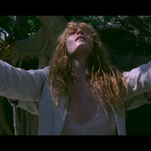 Still from Florence + the Machine's music video, "How Big How Blue How Beautiful." Florence Welch in white raising hands to sky.
