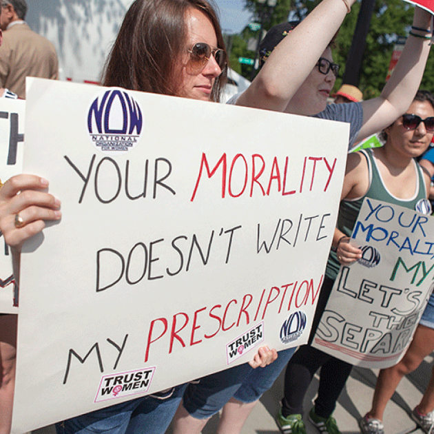 photo taken at a Washington, DC protest during the Supreme Court's hearing of Burwell v. Hobby Lobby (2014). A protestor holds a sign, "Your morality doesn't write my prescription." 