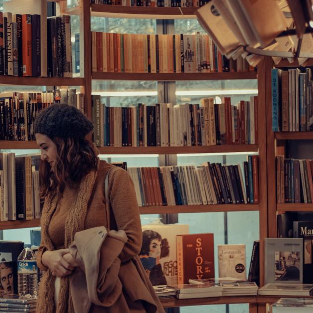 woman in hat browsing bookshelves